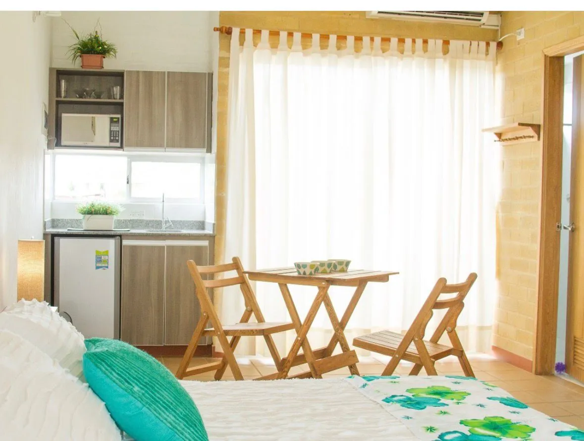 Cama, mesa junto a la ventana y equipo de aire acondicionado visibles en un apartamento de referencia de AVT